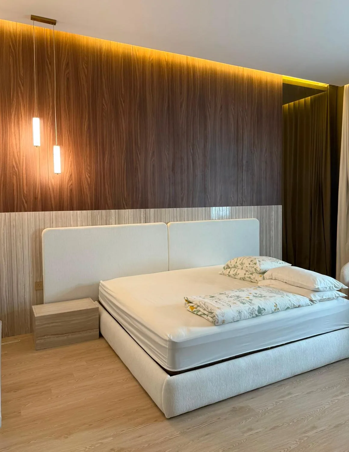Bedroom with a full-height walnut wall, warm cove light and a fluted oak lower panel