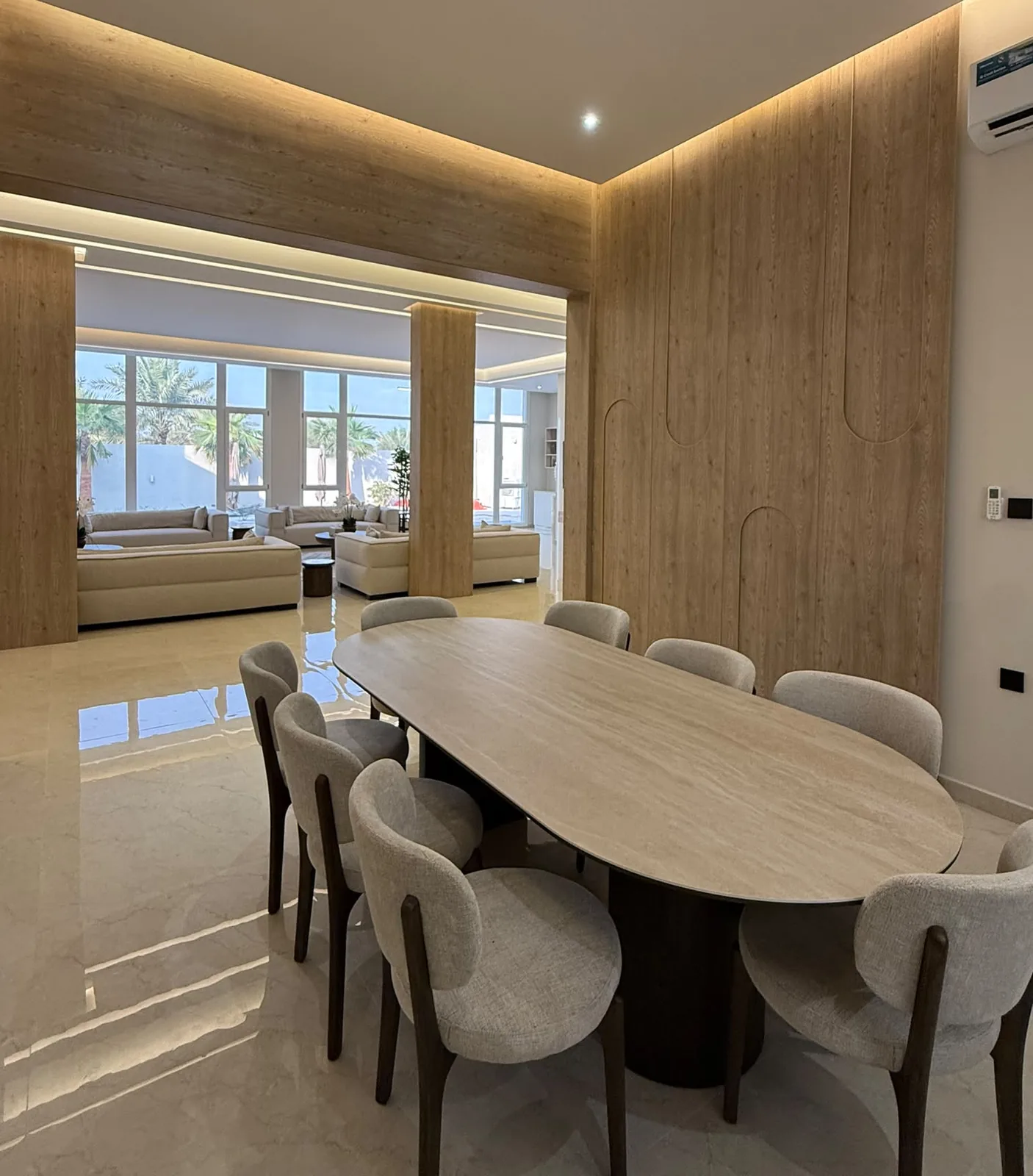 Dining room with a full-height oak-veneer wall, wood-clad columns and an oval dining table