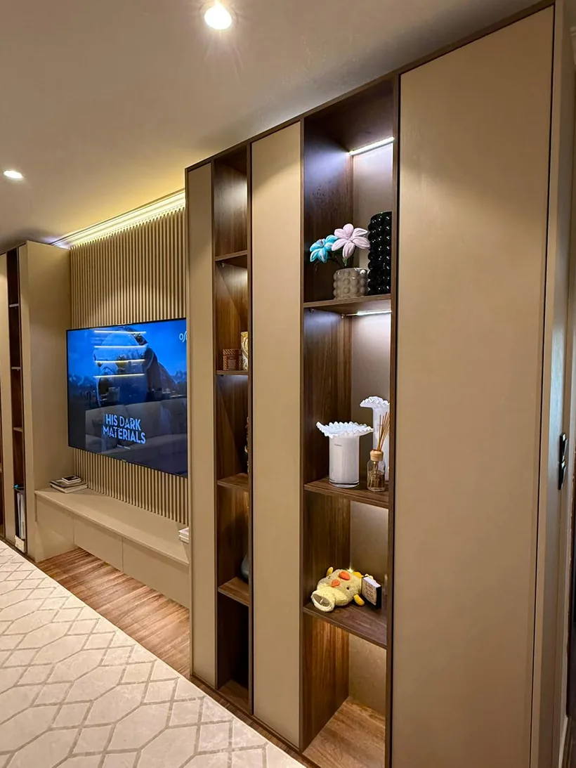 TV wall with walnut shelving and lit niches